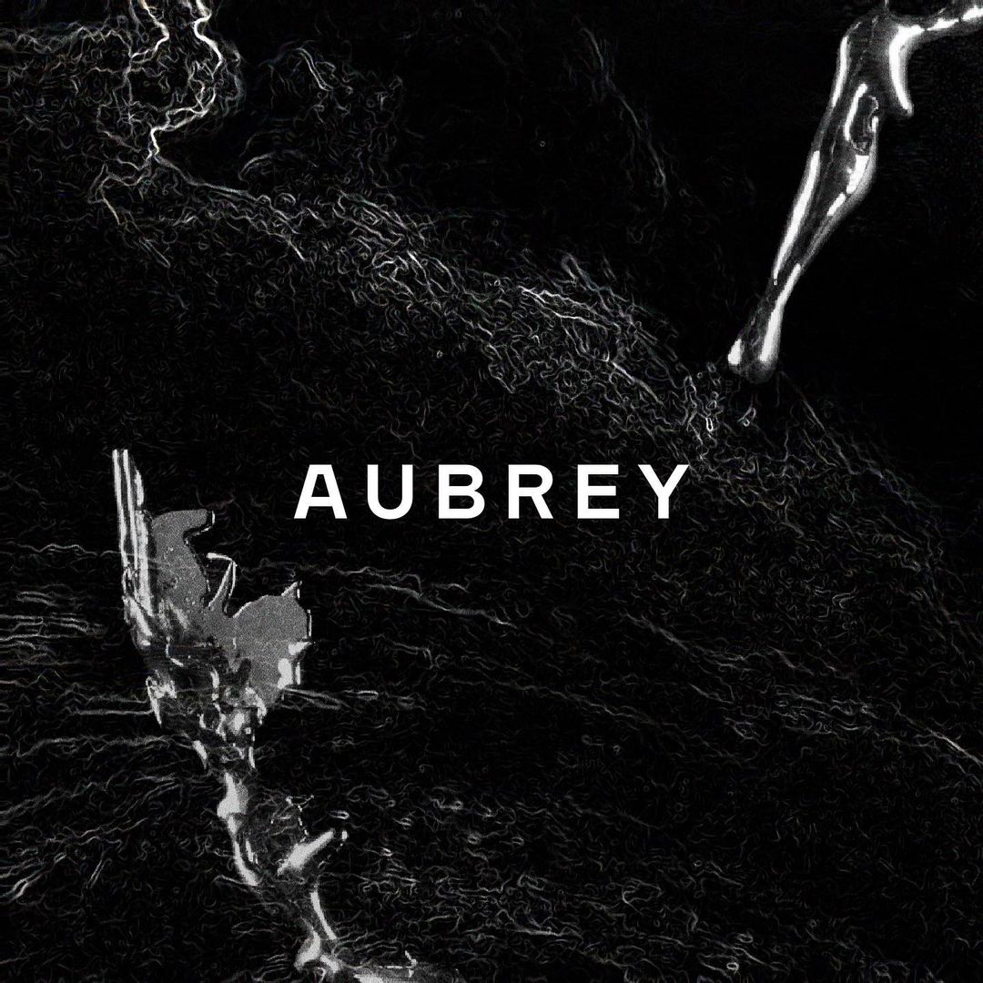 High contrast black and white abstract graphic with metallic chrome details and the word AUBREY centered in white uppercase text.