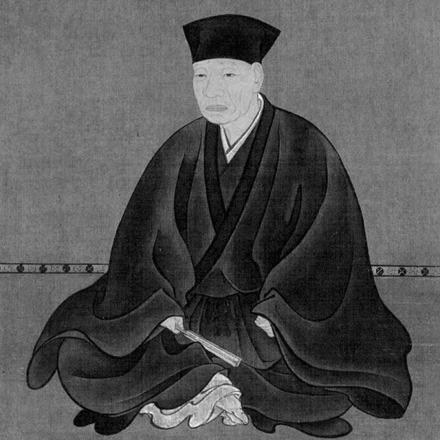 Japanese art portrait of an adult sitting indoors wearing a black robe and hat, holding a fan with a grey background.
