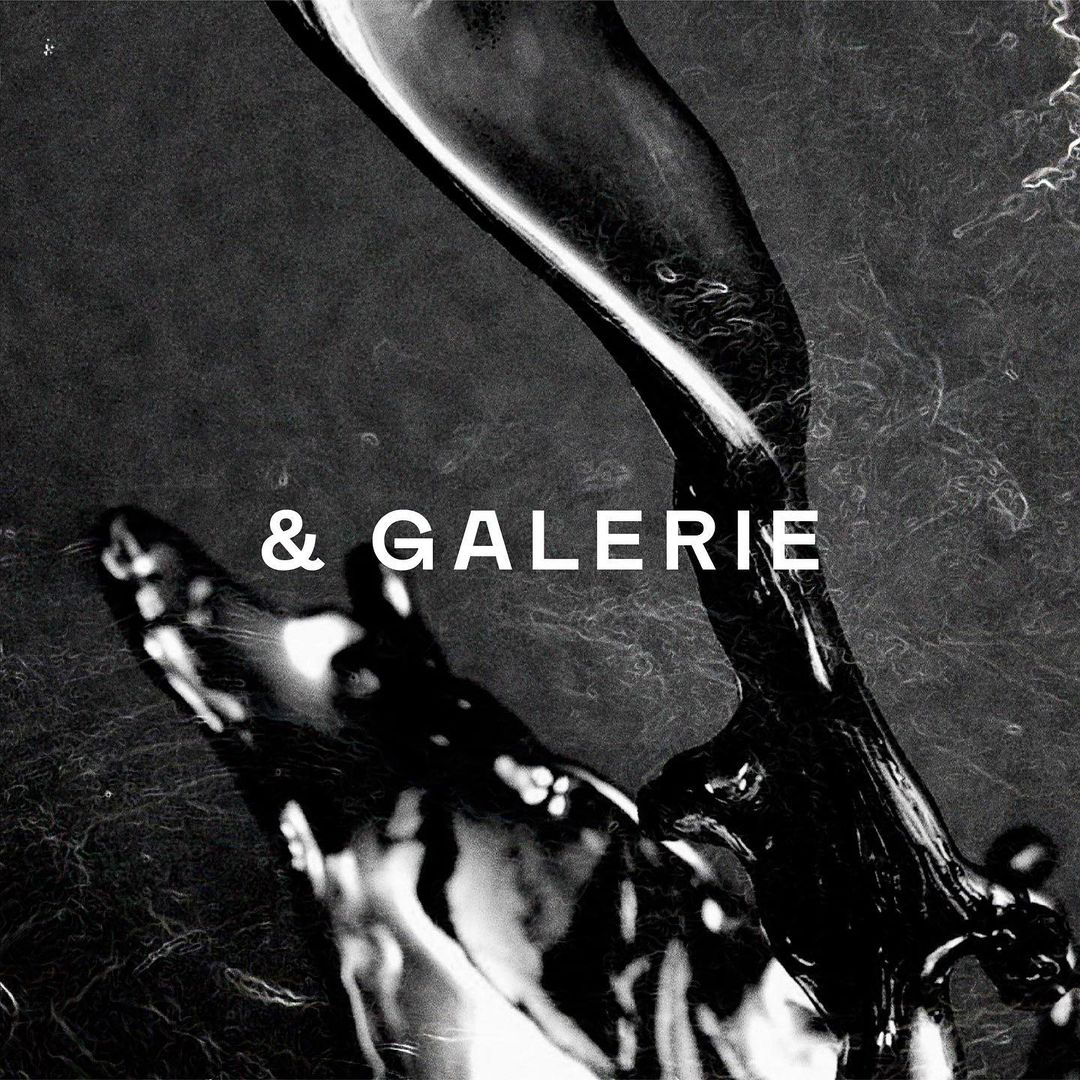 Abstract black and white image featuring a liquid cascade against a textured background, with the text '& GALERIE' centrally positioned.