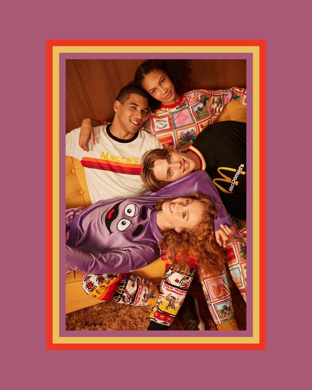 Four young adults wearing McDonald's-themed apparel lying on a mustard-colored sofa indoors. They are inside a picture frame with a colorful border.