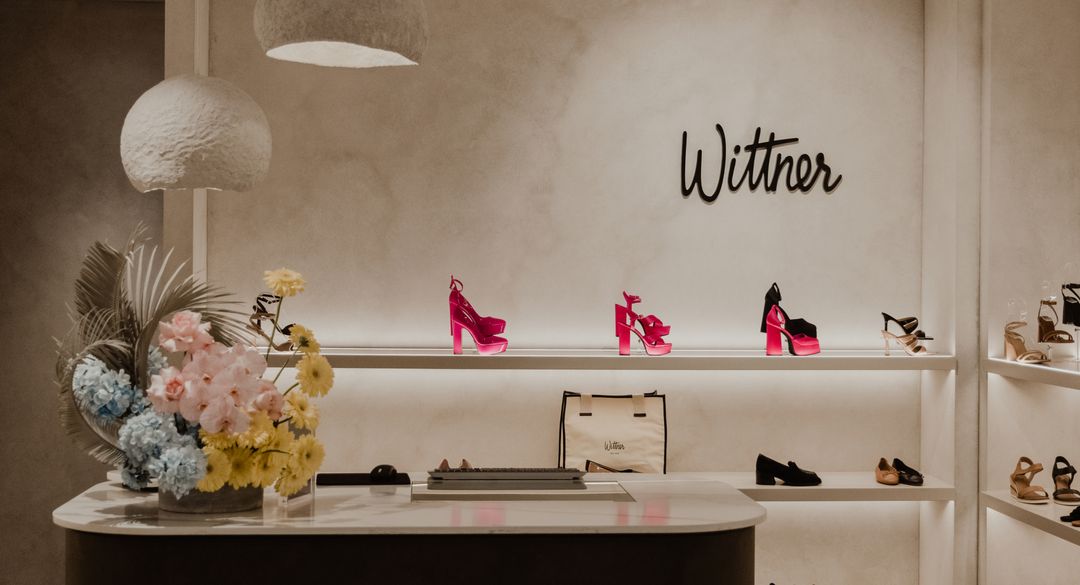Display of women's platform shoes in a retail setting with modern lighting, floral arrangement, and a 'Wittner' logo on the wall.