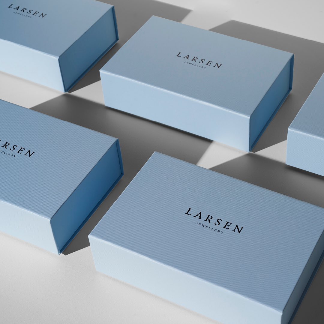 Several light blue Larsen Jewellery boxes arranged on a white surface with soft, diffused lighting creating subtle shadows.