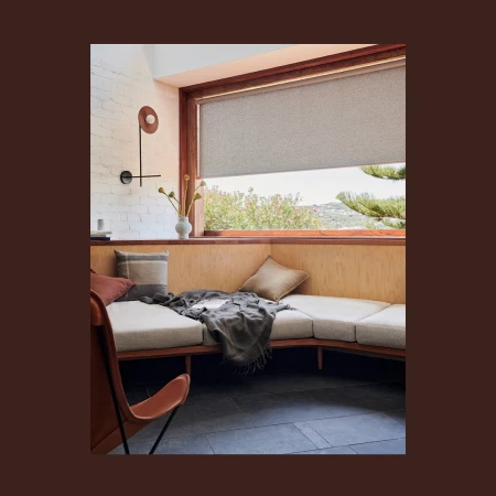 Modern interior featuring a daybed with soft cushions and throw blanket, bathed in natural light from a large window with a blind.