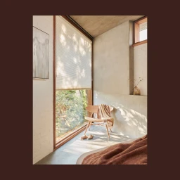 Sunlit modern bedroom interior featuring a wooden chair, large window, and textured blanket in Melbourne