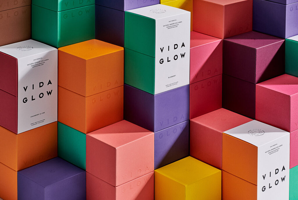 Stack of colorful Vida Glow boxes arranged in a geometric pattern for a vibrant beauty or wellness product display, showcasing product packaging.
