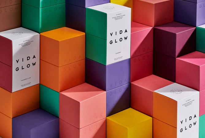 Stack of colorful Vida Glow boxes arranged in a geometric pattern for a vibrant beauty or wellness product display, showcasing product packaging.