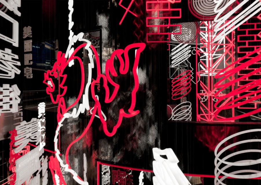 Abstract geometric art featuring red and white neon-style light installations against a dark background with blurred cityscapes visible.