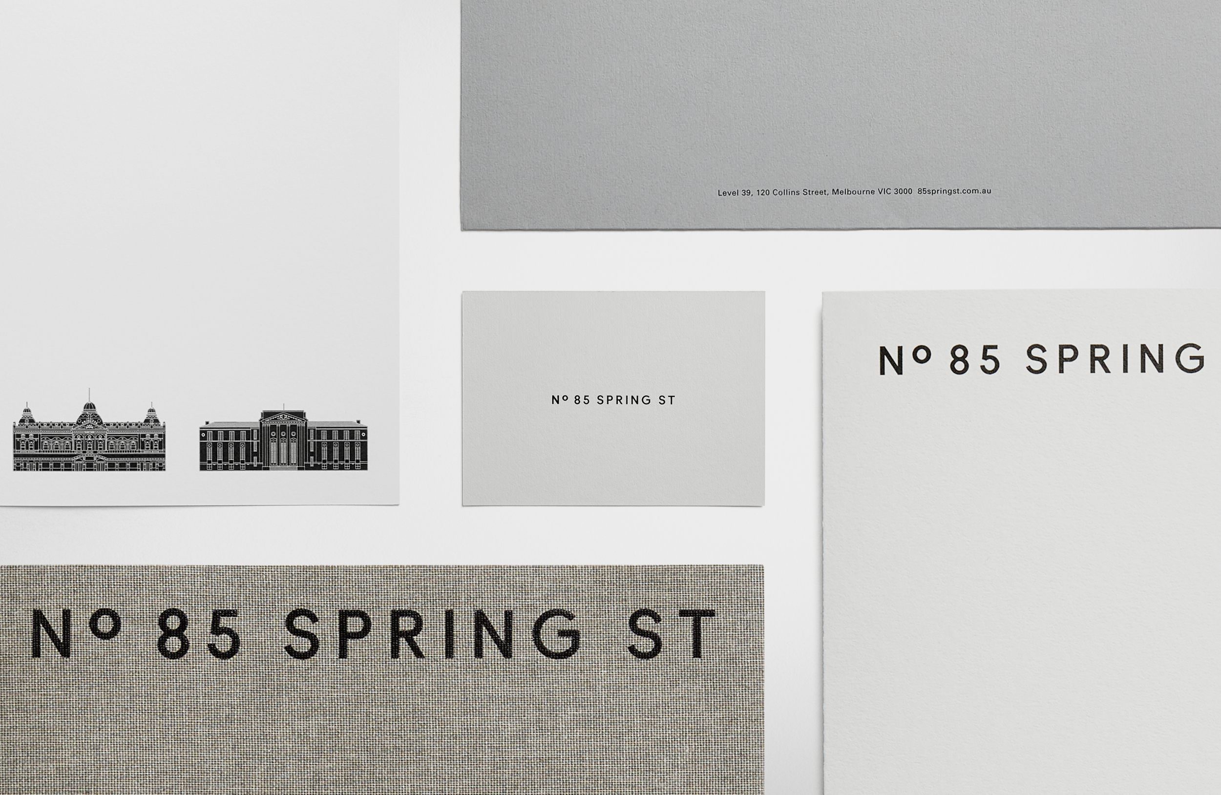 Close-up of graphic design materials featuring building illustrations and 'No. 85 Spring St' typography on paper and fabric.