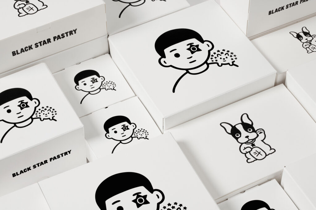 A graphic arrangement of white pastry boxes featuring cartoon drawings, some with 'Black Star Pastry' text, ideal for food packaging visuals.