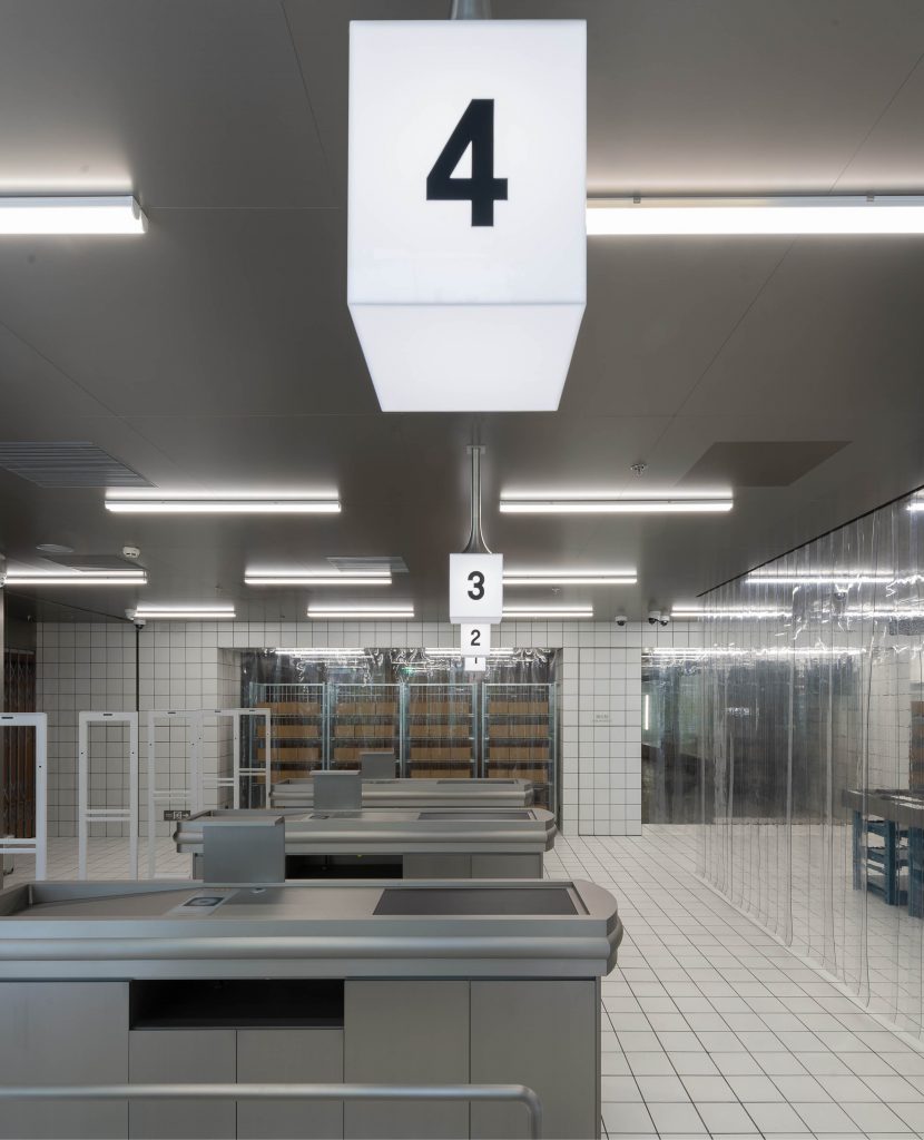 Empty supermarket checkout lanes with number signs and bright lights, creating a modern and minimalist ambiance for retail shopping.