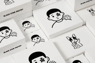 An arrangement of white cardboard pastry boxes printed with black graphic illustrations by Studio Ongarato