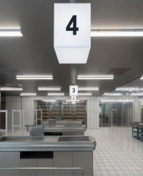 Interior of a modern commercial space with checkouts, white tiled walls, and hanging number sign four.