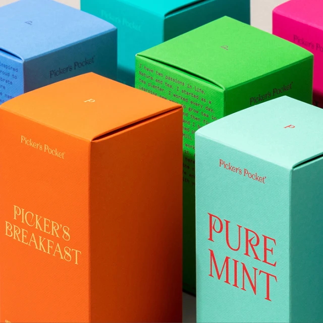 Arrangement of colorful Picker's Pocket tea boxes in hues of blue, orange, green, and aqua, featuring product branding and information.