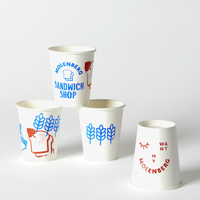 Four white paper cups with blue and red Molenberg Sandwich Shop branding in a studio shot, promoting a playful, vintage aesthetic.