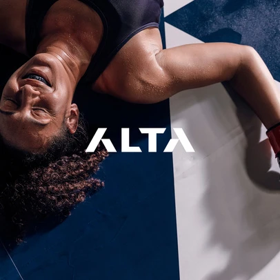 Adult female athlete lying on a blue and white checkered floor with closed eyes, sweat, and mouthguard in place after a workout.