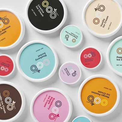 Overhead shot of multiple colorful ice cream containers, various flavors, minimalist design, arranged on a white background.