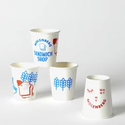 Four white paper cups with blue and red printed illustrations arranged against a clean white seamless studio background.