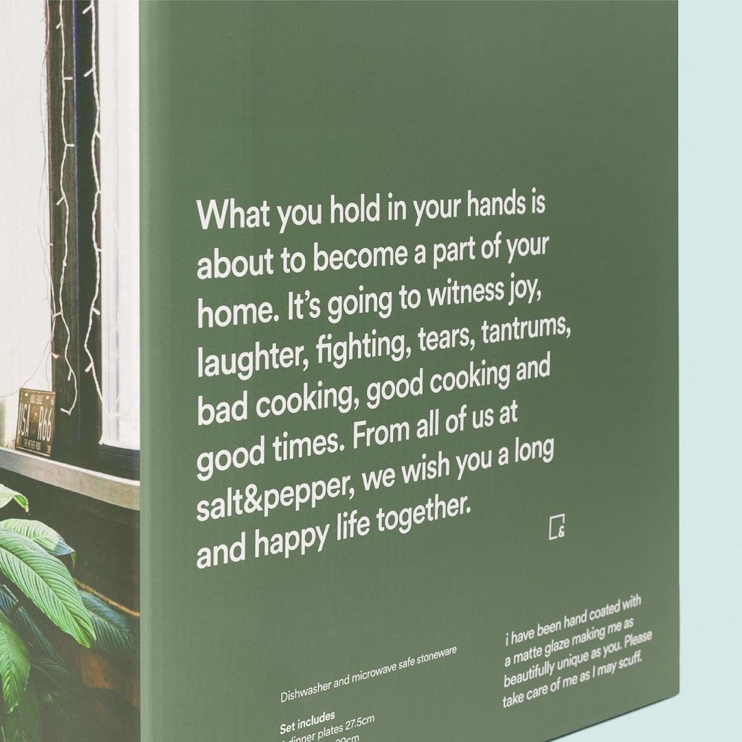 Close-up of a product box with descriptive white text against a green background, featuring indoor plants near a window.
