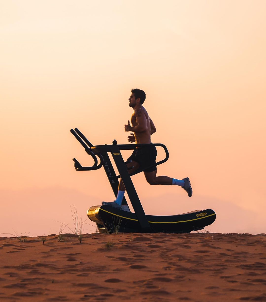 Athletic man with bare chest runs on treadmill outdoors in desert landscape with warm lighting, fitness and exercise, healthy lifestyle.