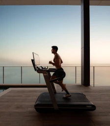 Man running on a treadmill on an outdoor terrace overlooking the ocean at sunset, captured by EVH in Sydney.