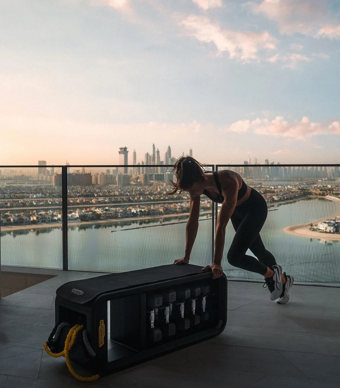 Woman in activewear exercising on a rooftop overlooking a city skyline at sunset