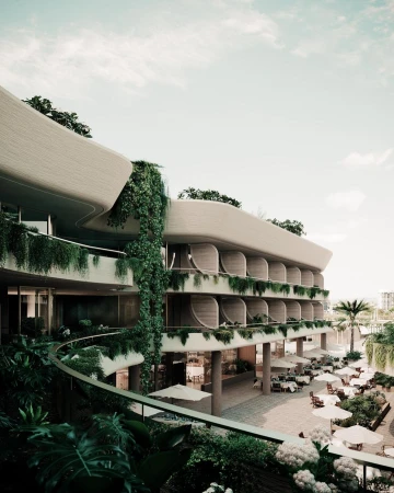 Exterior view of a multi-story hotel with curved balconies, lush greenery, outdoor dining area, and umbrellas on a sunny day.