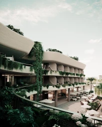 Modern multi-level building exterior in Sydney featuring curved balconies, cascading greenery, and an outdoor dining area with umbrellas.