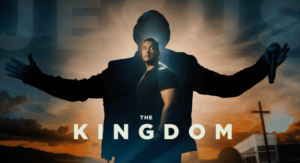 Man in suit stands with arms outstretched against a sunset with text 'The Kingdom' and a church in the background.