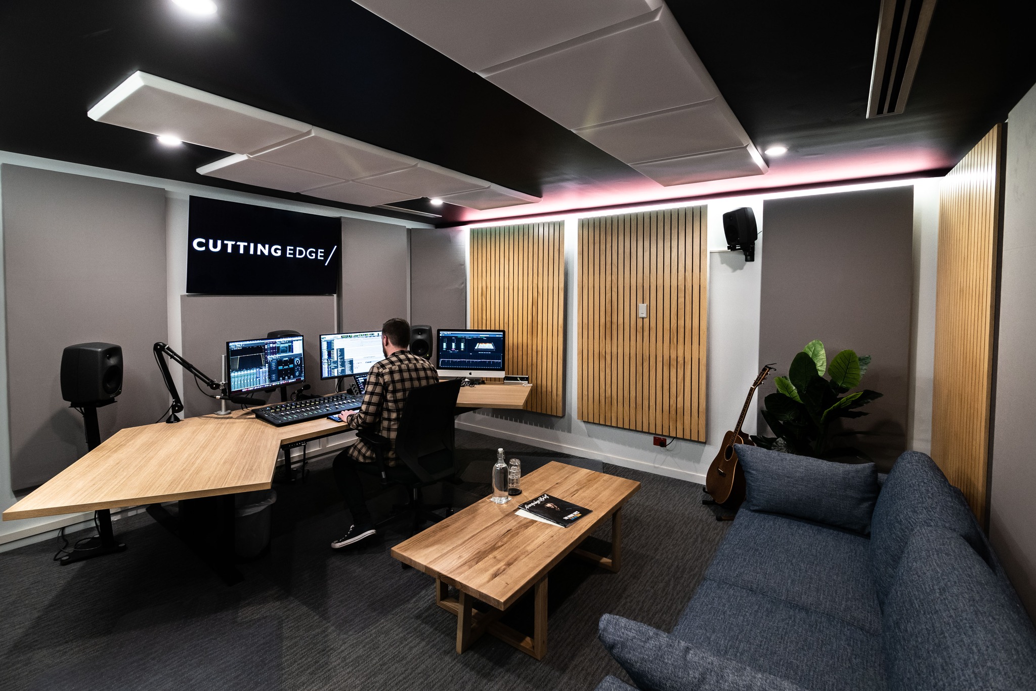 Adult male in a music recording studio works at an audio workstation with monitors, soundproofing, equipment, and a modern interior.
