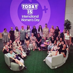 Group of women gathered in front of a purple International Women's Day display by Cutting Edge