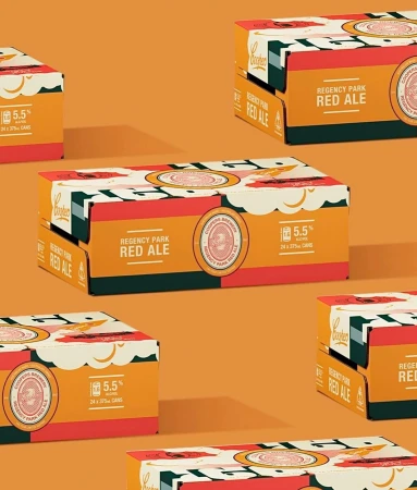 Several sealed cardboard cases of Coopers Brewery Regency Park Red Ale sit on an orange backdrop in a repeating, staggered pattern.