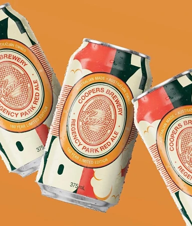 Three Coopers Brewery Regency Park Red Ale cans featuring vintage-style labels and condensation, set against an orange background.