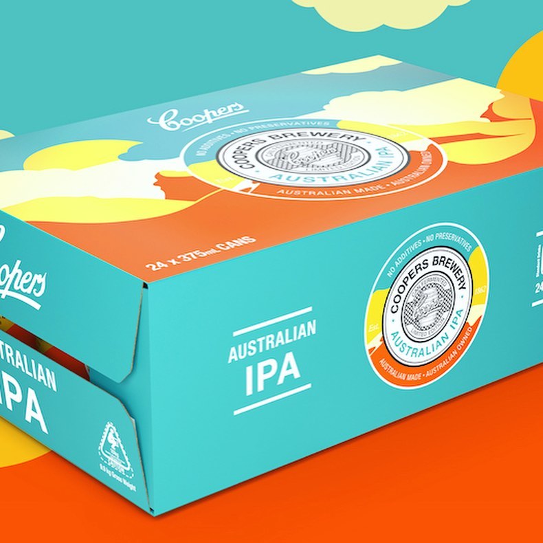 Close-up studio shot of a teal cardboard box of Coopers Australian IPA beer, with orange accents and graphics, against a teal and orange background.