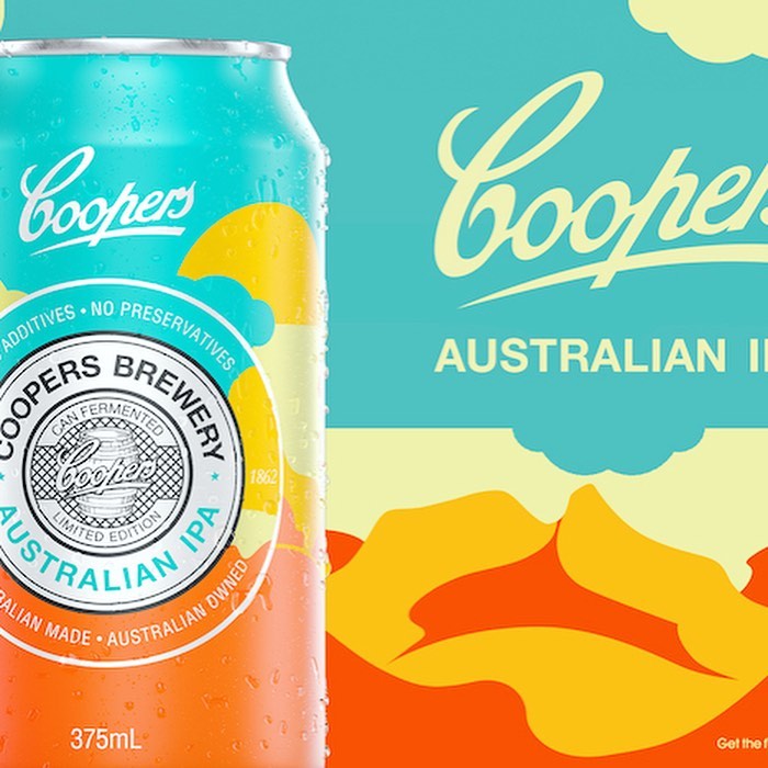 Eye-level close-up of a Cooper's Australian IPA beer can featuring shades of aqua, yellow, and orange and a graphic mountain range background.