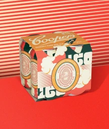Four-pack of Coopers Regency Park Red Ale cans in illustrated cardboard packaging on a red surface against a red-and-white striped background.