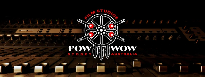 Close-up of a professional mixing console with faders, overlaid with the circular logo for Pow Wow Film Studios Sydney Australia.