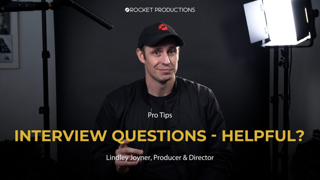 Adult male in a black jacket and baseball cap sits in front of a black background with video production lighting equipment and text overlay.