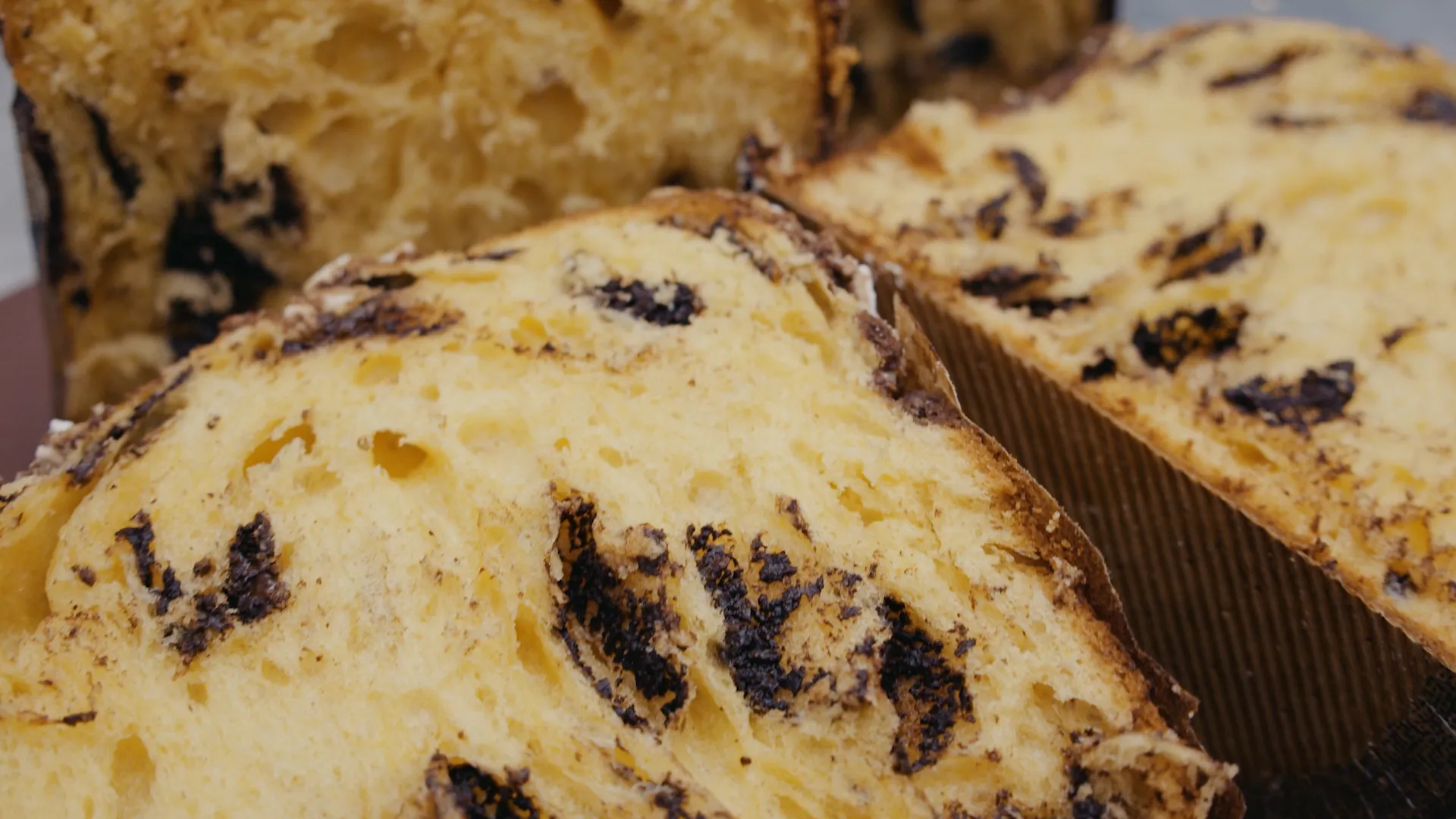 Close-up of sliced Panettone bread with chocolate chips. Delicious Italian sweet bread showcased in warm, inviting indoor food shot.