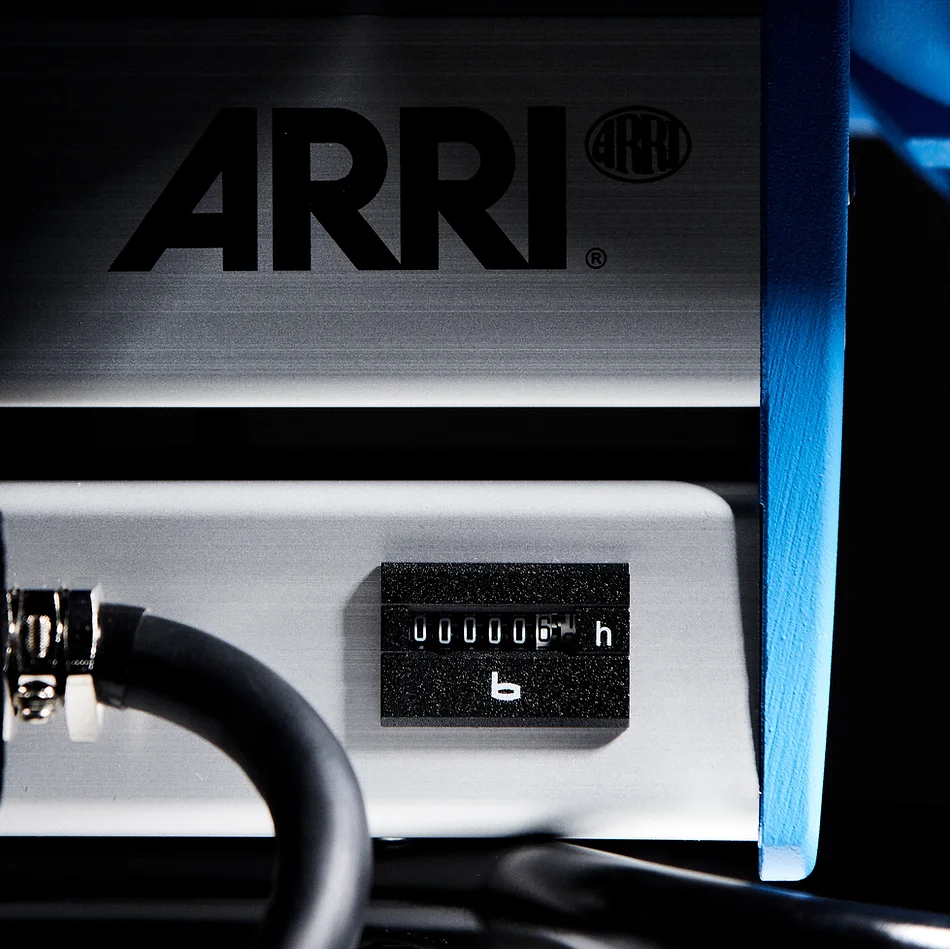 Close-up of the ARRI camera equipment with visible ARRI logo, settings and a black hose on the side on a dark background.