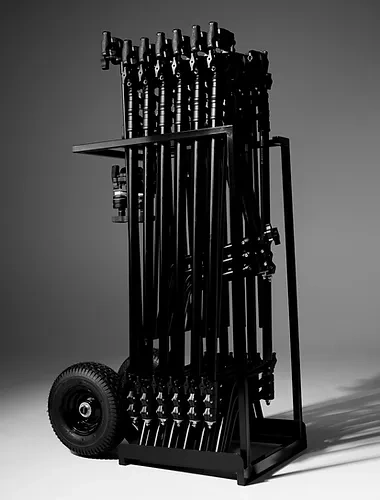 A black equipment cart loaded with multiple vertical black light stands and wheels against a plain grey studio backdrop