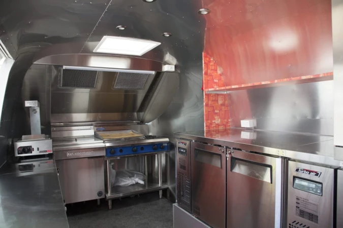 Commercial kitchen interior featuring stainless steel appliances including a range, oven, refrigeration, and ventilation system.
