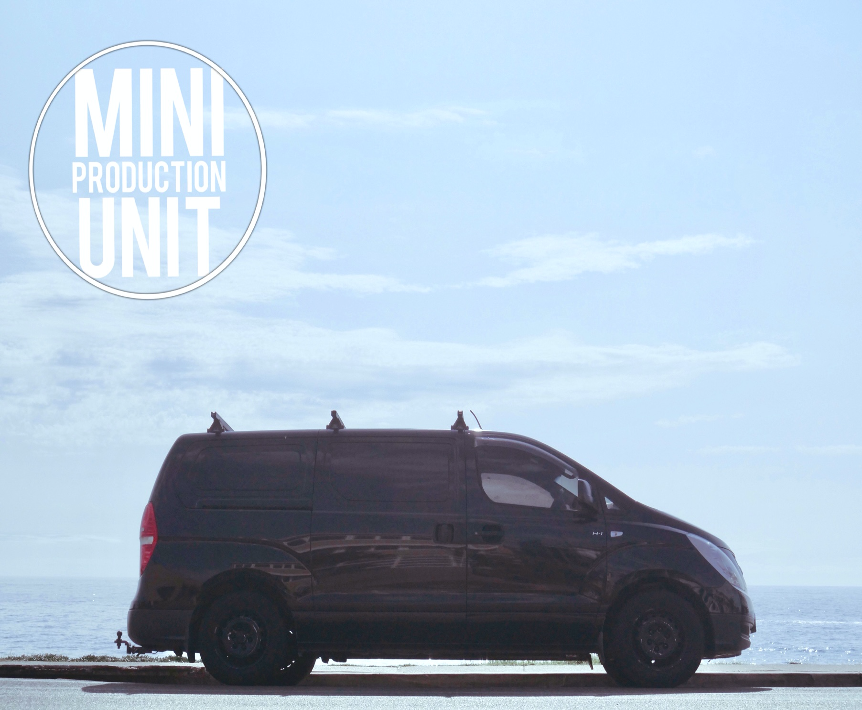 Black van parked near the ocean with a sky backdrop, minimalist composition, featuring the text 'Mini Production Unit'.