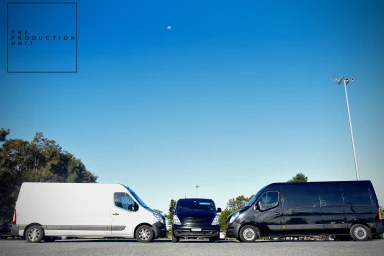 Three production vans parked in a row under a clear blue sky in Sydney, with a white van on the left and two black vans.
