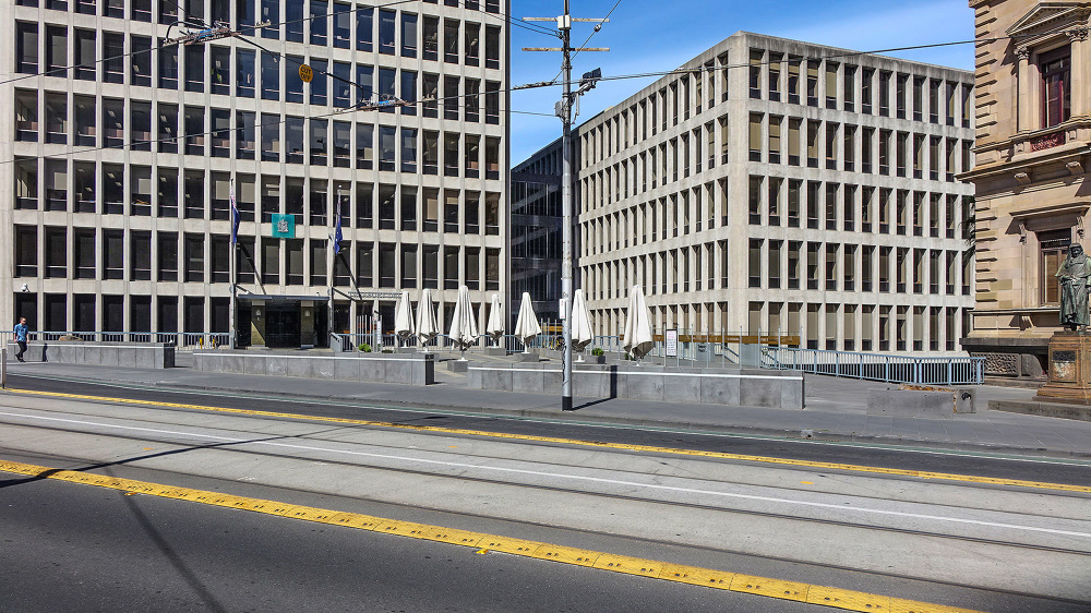 Street scene featuring modern architecture, office buildings, and a statue on a sunny day in Melbourne, Victoria, Australia.