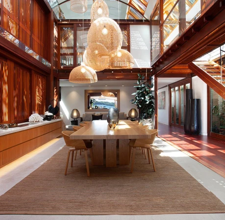 Spacious dining room interior with a large wooden table, woven pendant lights, and rich timber architecture in Sydney.