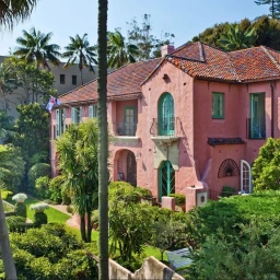Exterior view of a pink two-story house with terracotta tiled roof and lush green gardens in Sydney by Cobbold and Co
