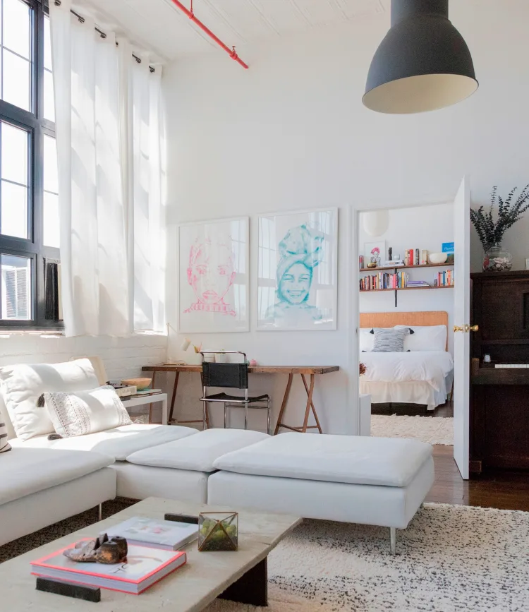 A bright living room with a white sectional sofa, light-colored rug, and framed art, creating a stylish and inviting home interior.