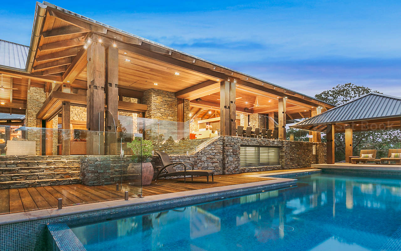 Exterior of a luxury home with a swimming pool and outdoor seating area at twilight, highlighting architecture, landscape, and lifestyle.