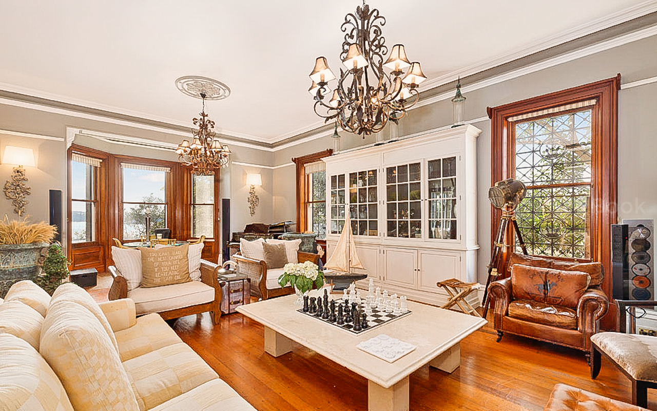 Living room interior featuring a cream-colored sofa, armchairs, a marble coffee table with a chessboard, and decorative lighting fixtures.