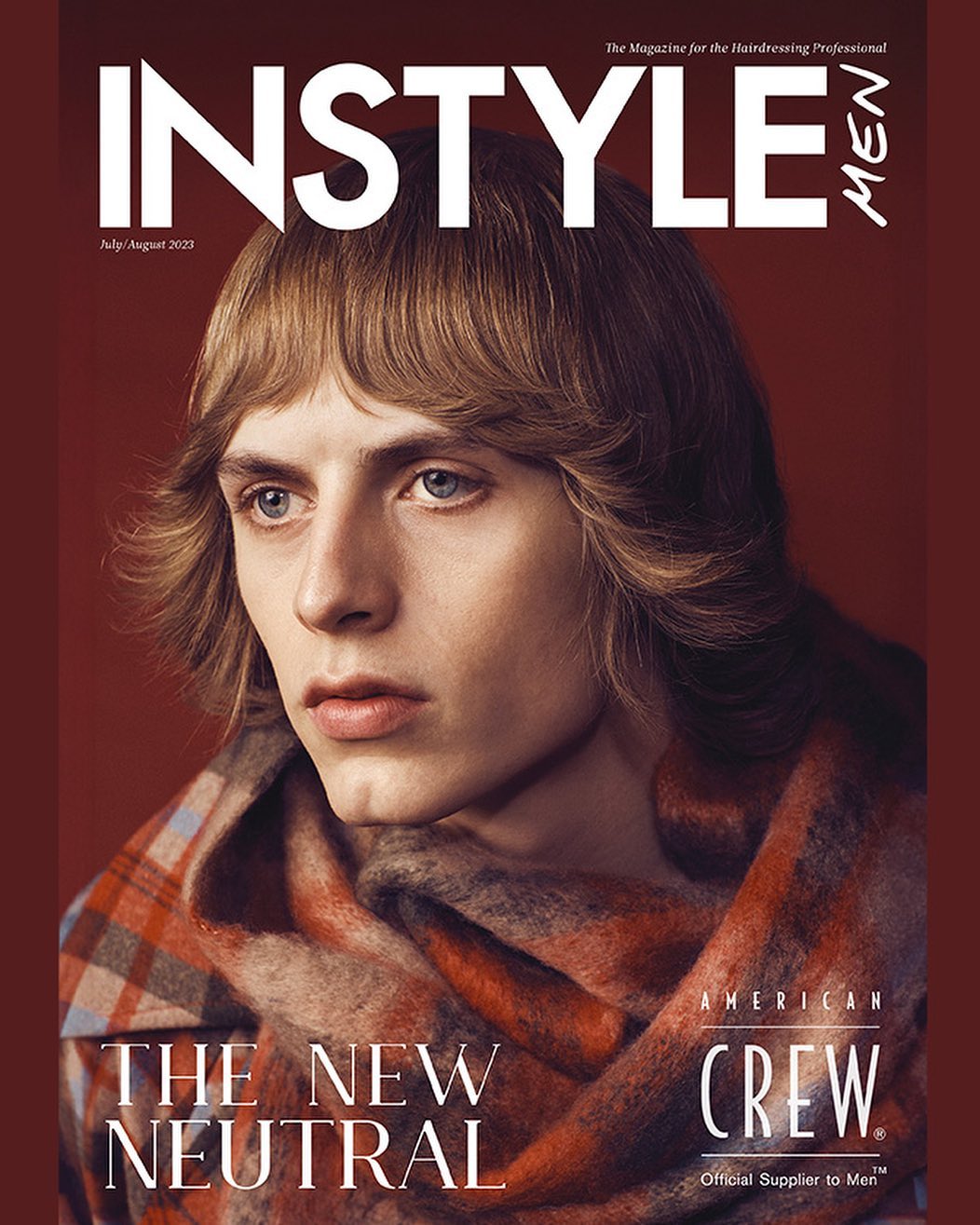 Magazine cover featuring a young adult man with long blonde hair, wearing a plaid scarf, against a reddish-brown background.